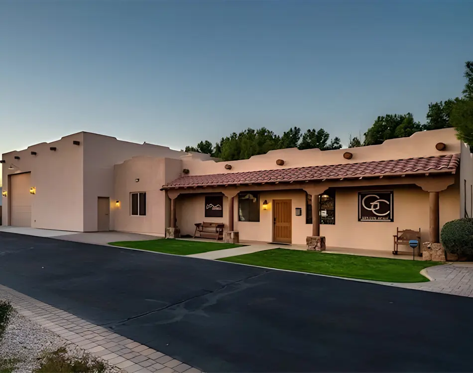 A building with a long driveway and grass on the ground.